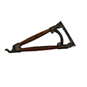 May include: A triangular shelf bracket featuring two dark brown wooden rods connected by dark metallic joints. The bracket includes a curved support arm and a decorative hook at the front tip, with a flat mounting plate at the rear for attachment.