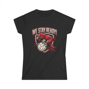 May include: A black short-sleeve t-shirt featuring a graphic print of a red hawk clutching a white volleyball inside a shield emblem. Above the emblem, the text WE STAY READY! is printed in a bold, light-colored, sans-serif font.