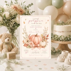 Puede incluir: Una tarjeta de invitación rectangular para baby shower con una ilustración central de una gran calabaza rosa rodeada de hojas de otoño y flores. El texto dice A LITTLE pumpkin IS ON THE WAY y Olivia Williams.