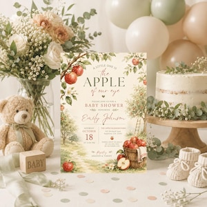 Puede incluir: Una tarjeta de invitación para baby shower con una ilustración de un huerto de manzanas, el texto A LITTLE ONE IS THE APPLE OF OUR EYE y los detalles del evento para Emily Johnson. El diseño incluye manzanas rojas y una cesta.