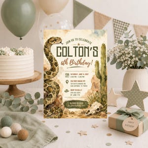 Puede incluir: Una tarjeta de invitación de cumpleaños rectangular con una ilustración en acuarela de una serpiente de cascabel, un cactus saguaro y un cráneo animal. El texto dice: JOIN US TO CELEBRATE COLTON'S 6th Birthday! SATURDAY, JUNE 14, 2027.