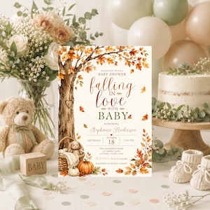 May include: A rectangular baby shower invitation card featuring a watercolour illustration of an autumn tree with orange and brown leaves, a basket with a plush bunny, and a pumpkin. The text reads: Please join us for a baby shower falling in love with baby honouring Stephanie Anderson, Saturday October 18, 2:00 PM, The Anderson Home, 123 Maple Lane, Autumn, State 12345, RSVP to Sarah at 123-456-7890, registered at Amazon & Target.