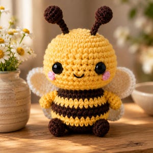 Peut inclure: Un jouet abeille en crochet avec une tête ronde jaune, de grands yeux noirs, des joues roses et deux antennes marron foncé. Le corps présente des rayures horizontales jaunes et marron foncé, des petits pieds marron et des ailes blanches.