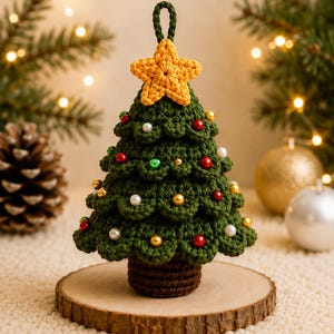 May include: A dark green crocheted Christmas tree ornament with a brown trunk and a yellow crocheted star on top. The tree is decorated with small red, gold, and white spherical beads throughout its layered branches and has a loop for hanging.