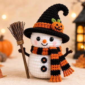 May include: A white crocheted snowman figurine wearing a black witch hat with an orange band and a small pumpkin accent. The snowman has a striped orange and black scarf, two black button details, and holds a miniature wooden broomstick.