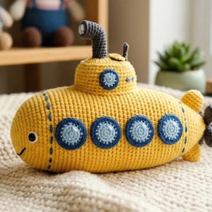 May include: A yellow crocheted submarine toy featuring a dark gray periscope, four circular blue portholes along the side, and a small propeller at the rear. The submarine has a stitched black eye and a simple curved line for a mouth on the front.