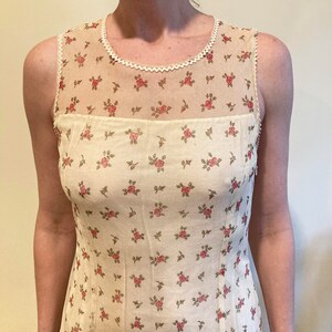 May include: A sleeveless white top with a floral pattern and a lace trim around the neckline.
