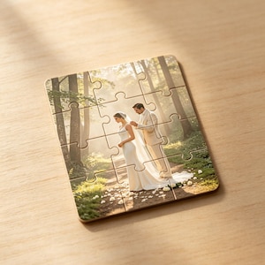 May include: A rectangular jigsaw puzzle featuring a printed photograph of a couple in wedding attire standing on a forest path. The puzzle consists of twelve interlocking pieces with rounded edges, displaying a scene of trees and sunlight.