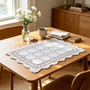Puede incluir: Un tapete rectangular de ganchillo blanco con un patrón repetitivo de motivos circulares y un borde festoneado. El intrincado tapete de encaje está elaborado con hilo blanco fino, mostrando un delicado diseño calado y texturizado.