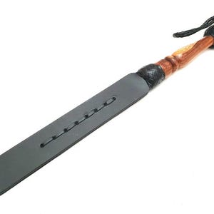 Handmade black leather paddle with wooden handle, crafted from premium genuine leather and polished hardwood. Durable leather craftsmanship accessory featuring braided leather accents, artisan handmade design, black leather paddle, leatherworking gift, handcrafted leather tool, rustic leather accessory, custom leather craftsmanship, traditional leather artisan product, premium quality leather item for collectors and handmade leather enthusiasts.
