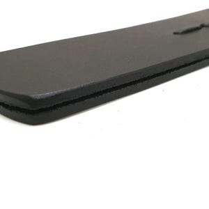 Handcrafted genuine leather paddle featuring black leather construction, polished wooden handle, and braided leather detailing. Premium artisan leatherwork accessory, custom handmade leather product, traditional leather craftsmanship, rustic leather gift, unique handcrafted item, leather collector accessory, durable genuine leather design, artisan crafted leather tool, high quality handmade leather creation.