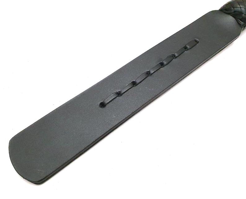 Premium handcrafted leather paddle made with black genuine leather and a smooth wooden handle. Features decorative braided leather details and expert craftsmanship. Handmade leather accessory, artisan leatherwork, custom leather paddle, leather gift idea, traditional leather craft, rustic leather decor, high quality handmade product, leather artisan creation, durable leather tool, unique handcrafted accessory.