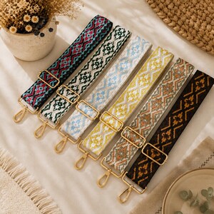 May include: Six adjustable bag straps featuring woven geometric patterns in various color combinations including black and red, green and white, light blue and white, yellow and white, orange and grey, and dark brown and gold, all with gold metal hardware.