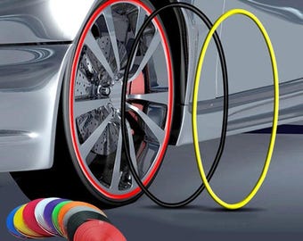 May include: A set of circular adhesive rim protector strips in various colors including red, yellow, black, blue, and orange. The strips are shown coiled in rolls and applied as a decorative border around the edge of a silver car wheel rim.