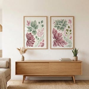 K&ouml;nnte beinhalten: Zwei gerahmte Wandbilder mit botanischen Aquarellillustrationen in gedeckten Gr&uuml;n-, Altrosa- und Dunkelburgundert&ouml;nen. Die Kunstwerke zeigen verschiedene stilisierte Bl&auml;tter, florale Formen und organische Pflanzenmotive auf wei&szlig;em Grund.
