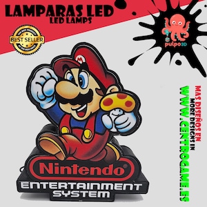 May include: A decorative LED lamp featuring a colourful graphic of Mario holding a mushroom, mounted on a black base with the Nintendo Entertainment System logo. The design includes text reading LAMPARAS LED, BEST SELLER, and pulpo3D.