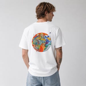May include: A white short-sleeved t-shirt featuring a large, circular graphic on the back. The design is a vibrant, multi-colored illustration depicting a complex scene with stylized waves, floral patterns, and various figures in red, blue, and yellow.