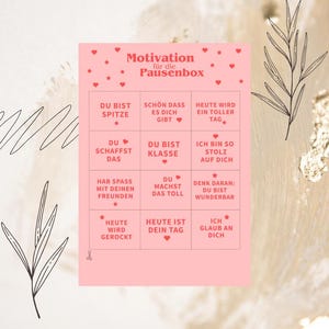 以下が含まれることがあります： 上部に「Motivation für die Pausenbox」というテキストが記載された長方形のピンク色のカード。その下にはドイツ語のモチベーションを高めるフレーズが書かれた12個の正方形のグリッドがあり、小さな赤いハートと星、そして小さなハサミのアイコンで装飾されています。