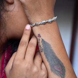 May include: A silver-toned bracelet featuring a series of small, detailed fish-shaped charms linked together. The metal has an oxidized finish that highlights the textured scales and fins of each individual fish element along the chain.