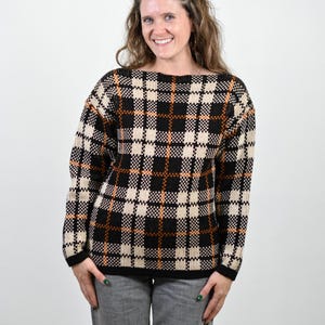 May include: A black, white, and orange plaid sweater with a boat neck.