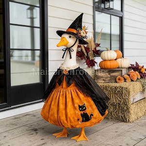 May include: A white goose figurine wearing a black witch hat with an orange band and floral accents, a black cape, and an orange dress featuring a black cat graphic. The goose has a yellow beak and orange feet, with a small pumpkin charm at the neck.