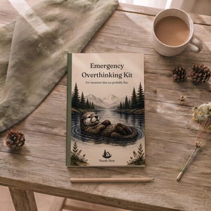 May include: A rectangular book titled Emergency Overthinking Kit with the subtitle For situations that are probably fine. The cover features an illustration of an otter floating in a lake surrounded by pine trees and mountains, with the North Nest logo.