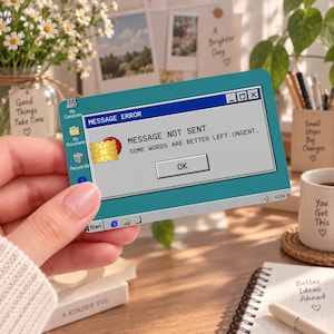 May include: A rectangular credit card featuring a teal background with a retro computer operating system interface. The screen displays a message error box with the text MESSAGE NOT SENT and SOME WORDS ARE BETTER LEFT UNSENT with an OK button.
