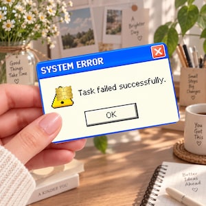 May include: A rectangular card featuring a blue and white computer system error pop-up window. The text reads SYSTEM ERROR and Task failed successfully. A yellow warning triangle icon with a gold chip overlay and an OK button are visible.