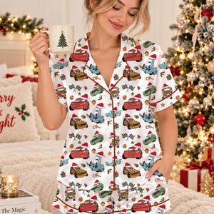 Può includere: Un set di pigiama in raso bianco composto da una camicia a maniche corte abbottonata e pantaloncini coordinati. Il tessuto presenta un motivo ripetuto di auto dei cartoni animati con cappelli di Babbo Natale, regali e bandiere a scacchi.