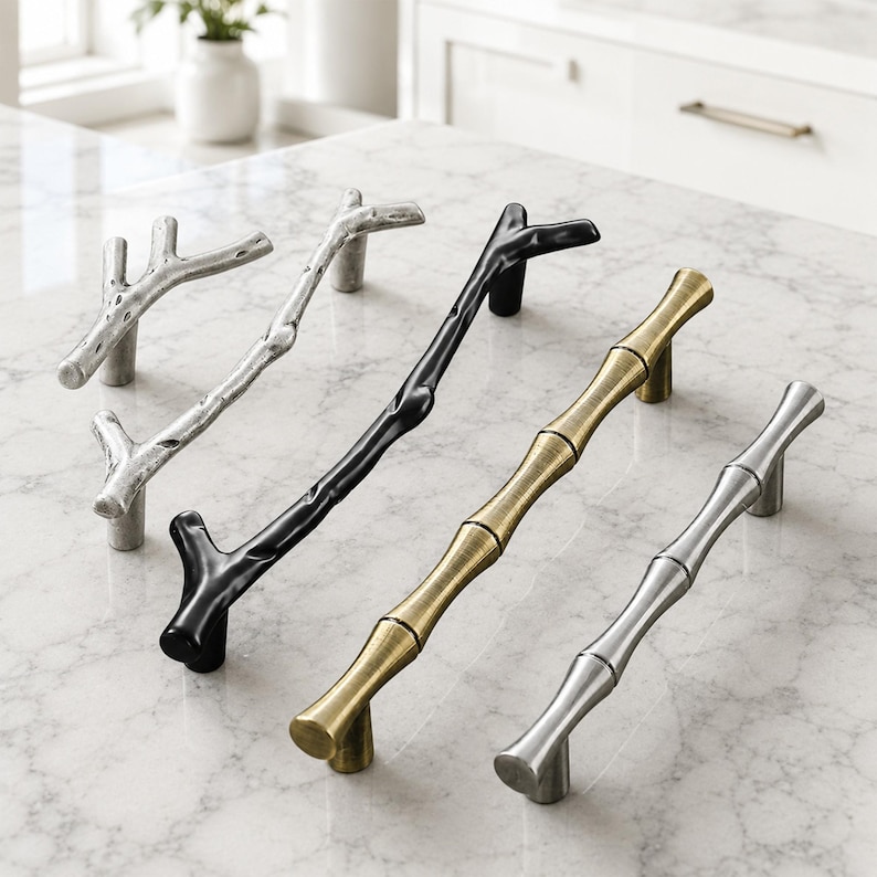 May include: Four cabinet pulls arranged in a row. Two pulls feature a textured, branch-like design in silver and black finishes. Two pulls feature a smooth, segmented bamboo-inspired design in brushed gold and polished silver metallic finishes.