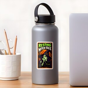 May include: A rectangular sticker on a gray water bottle featuring a green-skinned witch in a black hat and a black cat. The text reads RESTING WITCH FACE and BAD CAT SUPPLY. The background shows an orange moon and dark trees.