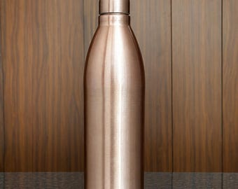 May include: A cylindrical water bottle with a metallic rose gold finish and a matching screw-top lid. The bottle features a smooth, polished surface that reflects light, with a tapered neck leading to a rounded cap at the top of the vessel.