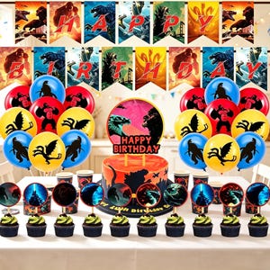 Puede incluir: Un set de decoración para fiestas con imágenes de Godzilla y King Kong, que incluye una pancarta de Happy Birthday, un adorno para pastel, globos coloridos con siluetas de monstruos y adornos para cupcakes con gráficos circulares.