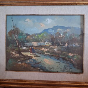 May include: An oil painting in a gold frame depicting a landscape with a stream, two figures walking, trees, and distant mountains under a blue sky. The scene features earthy tones of brown, green, and blue with visible brushstrokes throughout.