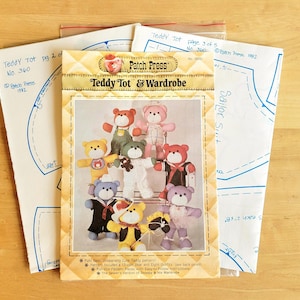 May include: A sewing pattern titled "Teddy Tot & Wardrobe" featuring illustrations of teddy bears in various outfits. The pattern includes instructions and full-size pattern pieces. Additional pattern sheets are visible, with text including "Teddy Tot" and "Sailor Suit."