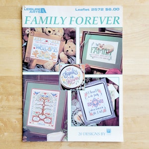 May include: A leaflet titled "FAMILY FOREVER" with various cross-stitch designs. The cover features framed samplers with the words "WELCOME" and "FAMILY", plus a family tree design. The leaflet includes the text "20 DESIGNS BY".