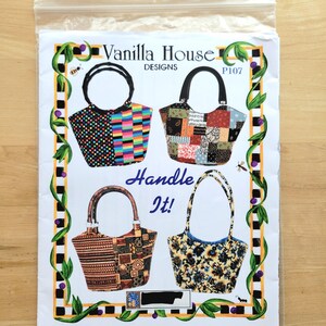 May include: A pattern sheet for tote bags, featuring four different bag designs. The sheet is labeled "Vanilla House Designs" and includes the text "Handle It!" The bags have various patterns, including patchwork, geometric, and floral designs. The sheet is in a clear plastic bag.