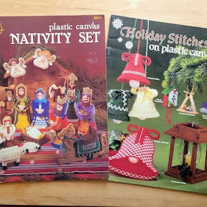 May include: Two instructional craft booklets for plastic canvas projects. The left booklet is titled Plastic Canvas Nativity Set and features a nativity scene. The right booklet is titled Holiday Stitches on plastic canvas and shows various ornaments.