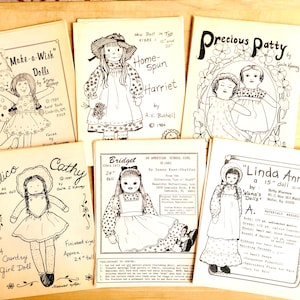 May include: A collection of eight vintage doll sewing patterns. The patterns feature illustrations of dolls with different names, including "Make-a-Wish Dolls", "Home-Spun Harriet", "Precious Patty", "Calico", "Cathy", "Bridget", and "Linda Ann".