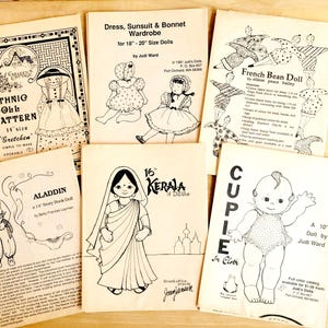 May include: A collection of eight doll-making patterns. The patterns include a French Bean Doll, a 10-inch doll, a 14-inch doll, a 16-inch doll, an Aladdin doll, an Ethnic Doll, and a Kerala doll. The patterns are printed on white paper with black ink.
