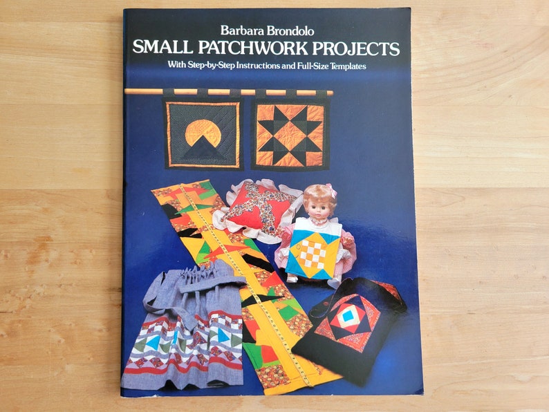 May include: A book titled "SMALL PATCHWORK PROJECTS" by Barbara Brondolo, with step-by-step instructions and full-size templates. The cover features patchwork designs, including a doll wearing a patchwork outfit and other small patchwork projects.