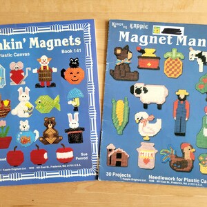 May include: Two craft books with colorful covers featuring plastic canvas needlework projects. The book on the left is titled "Makin' Magnets with Plastic Canvas" and the book on the right is titled "Magnet Mania 30 Projects Needlework for Plastic Canvas".