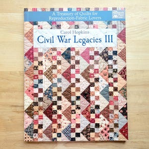 May include: A book titled "Civil War Legacies III" by Carol Hopkins. The cover features a colorful patchwork quilt design with various fabric patterns in shades of red, brown, and cream. The book is part of the "A Treasury of Quilts for Reproduction-Fabric Lovers" series.