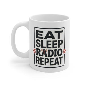 Peut inclure: Mug en céramique blanche avec le texte "EAT SLEEP RADIO REPEAT" dans un cadre rectangulaire noir. Le mot "RADIO" comporte un symbole d'onde radio. La tasse a une anse blanche.