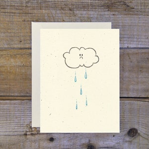 Peut inclure: Une carte blanche avec un nuage gris avec un visage triste et des gouttes de pluie bleues qui tombent.