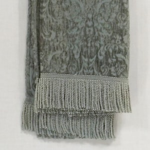 May include: A soft, light blue throw blanket with a damask pattern and a fringe border.