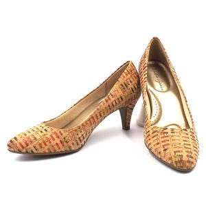 May include: A pair of low-heeled pumps with a cork-like woven pattern in shades of tan, red, and green. The shoes have a pointed toe and a small heel. The interior is a light gold color.