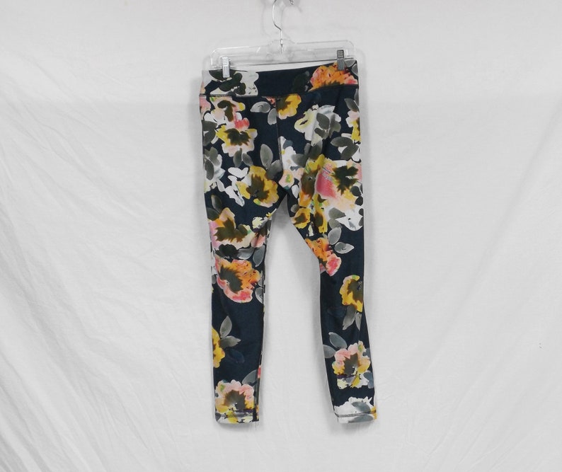 May include: Black leggings with a floral print featuring yellow, pink, and white flowers.