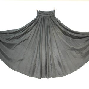 Puede incluir: Una falda larga y fluida de color negro con cintura elástica. La falda está hecha de una tela ligera y tiene una silueta amplia y fluida.