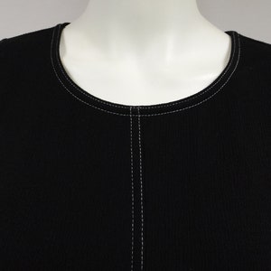 May include: Black sleeveless top with white stitching around the neckline and down the center front.